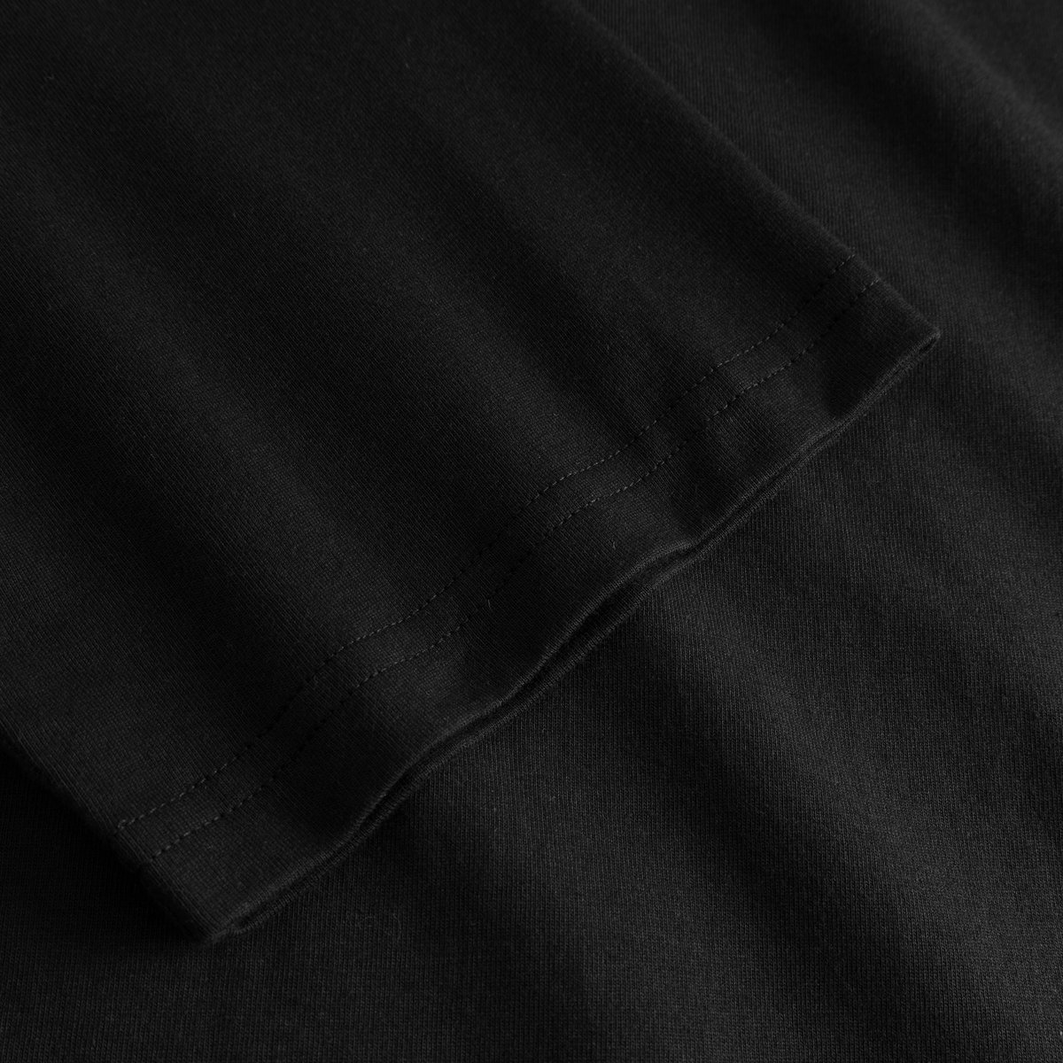 Close-up of the sleeve on the T-shirt Vadstena Painted Swans Black, showing the soft organic cotton fabric and neat hem.