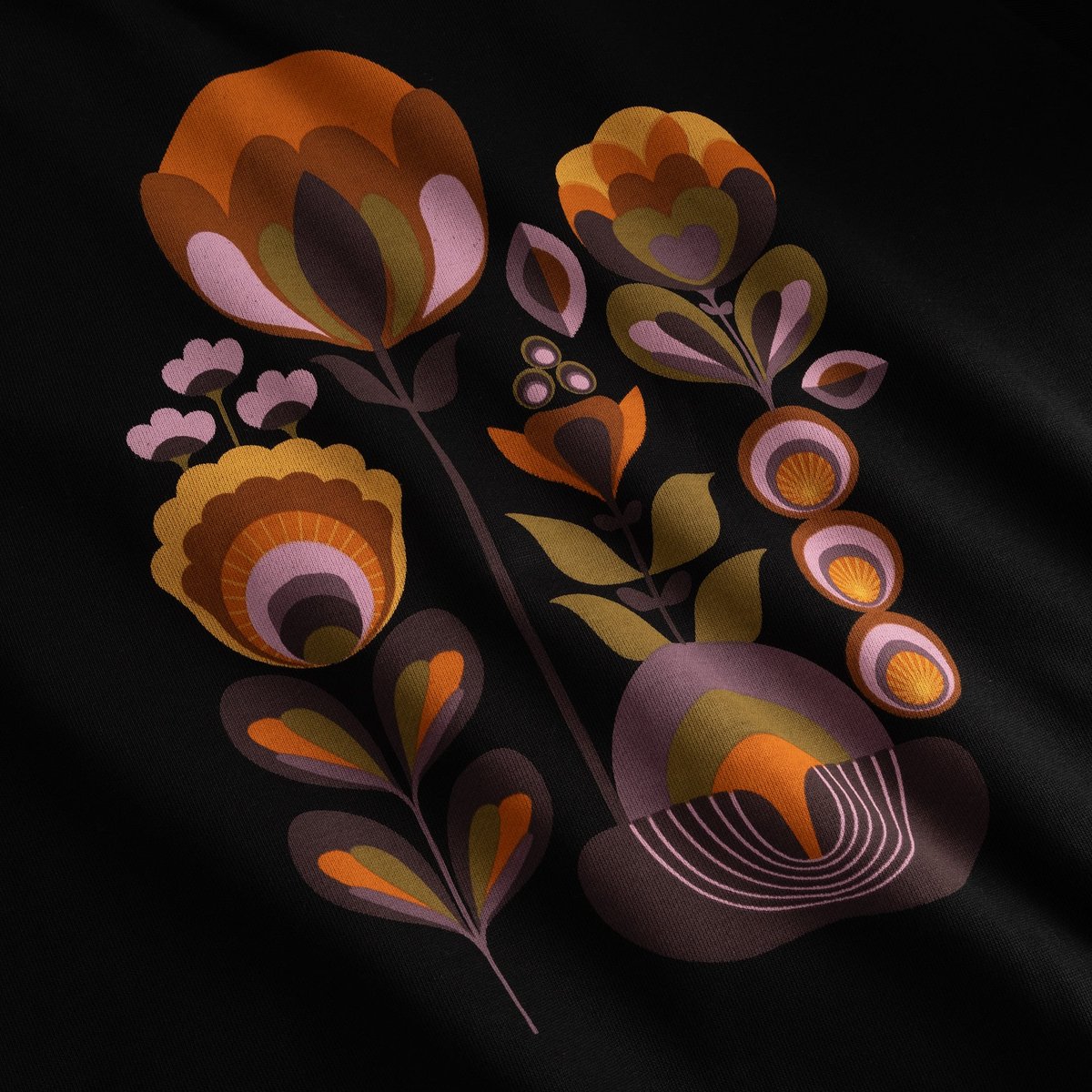 A close-up view of the Autumn Harvest graphic on the black Ystad sweatshirt, showing the warm floral print in detail.