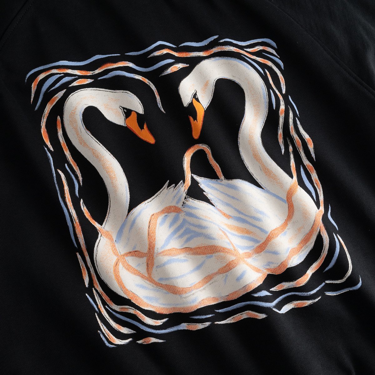 A detailed close-up of the artistic painted swans graphic on the black Ystad sweatshirt.