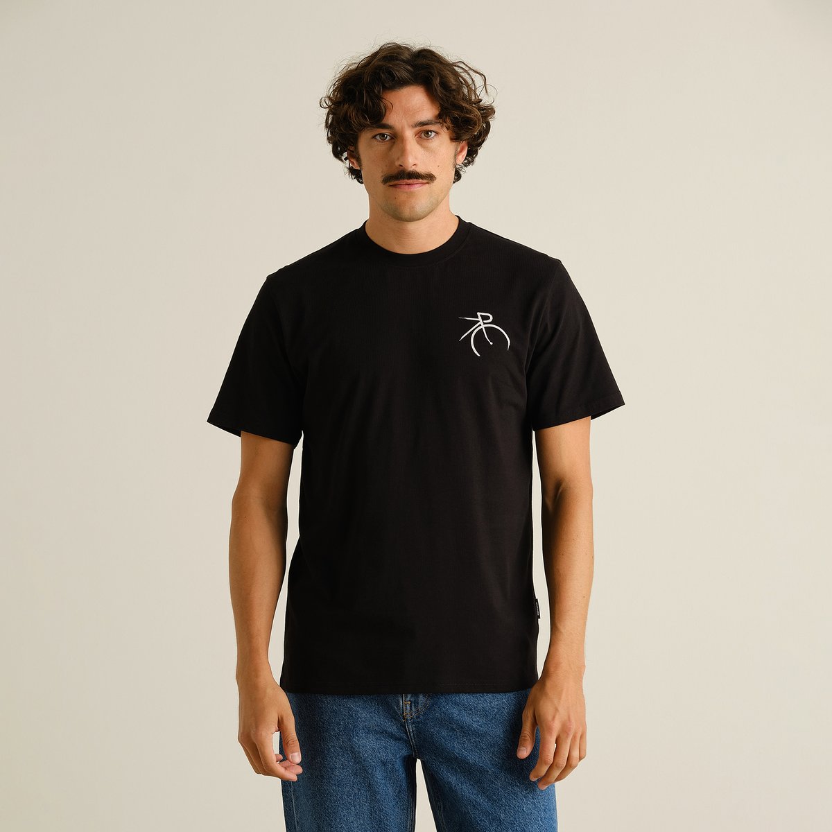 Model wears black T-shirt Stockholm featuring a small white painted side bike graphic on the chest, paired with blue jeans.