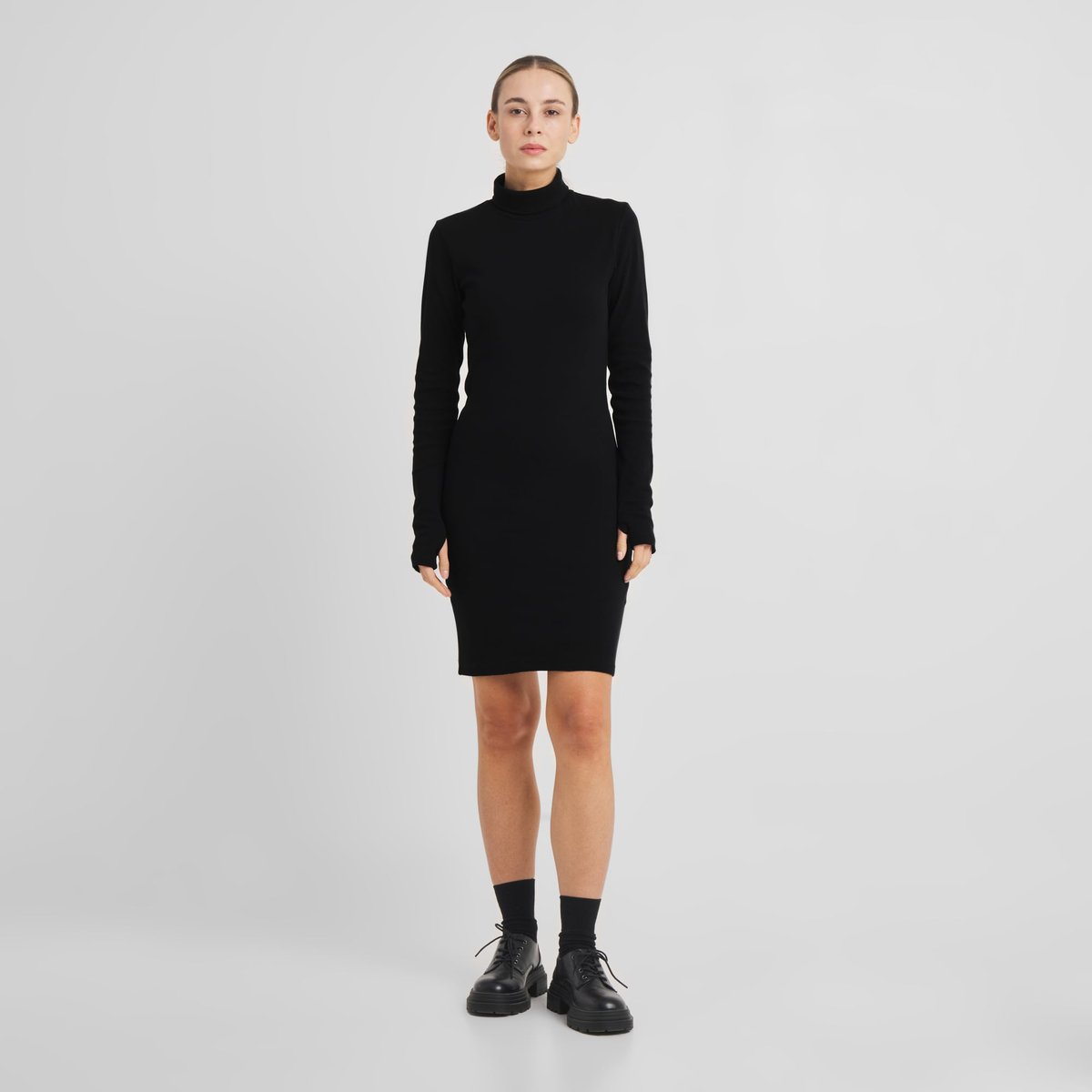 Ein Model trägt das schwarze Rippkleid Lunsen, ein kurzes Rollkragenkleid mit langen Ärmeln und schmaler Passform.