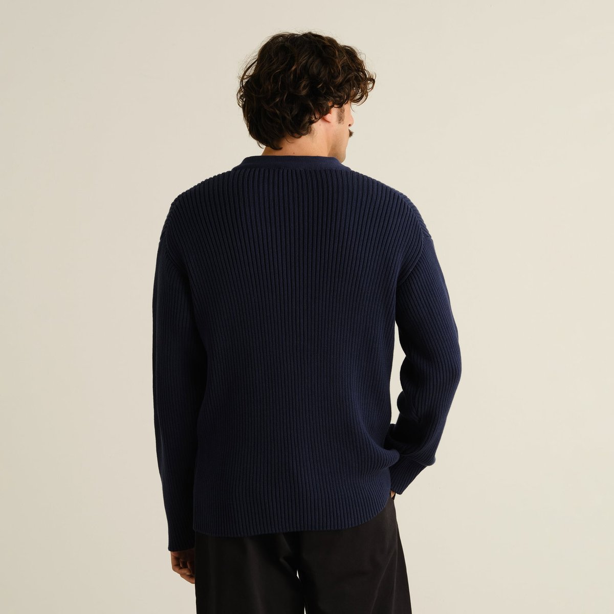 Modell sedd bakifrån i den marinblå, grovribbstickade Cardigan Huuki med ledig passform.