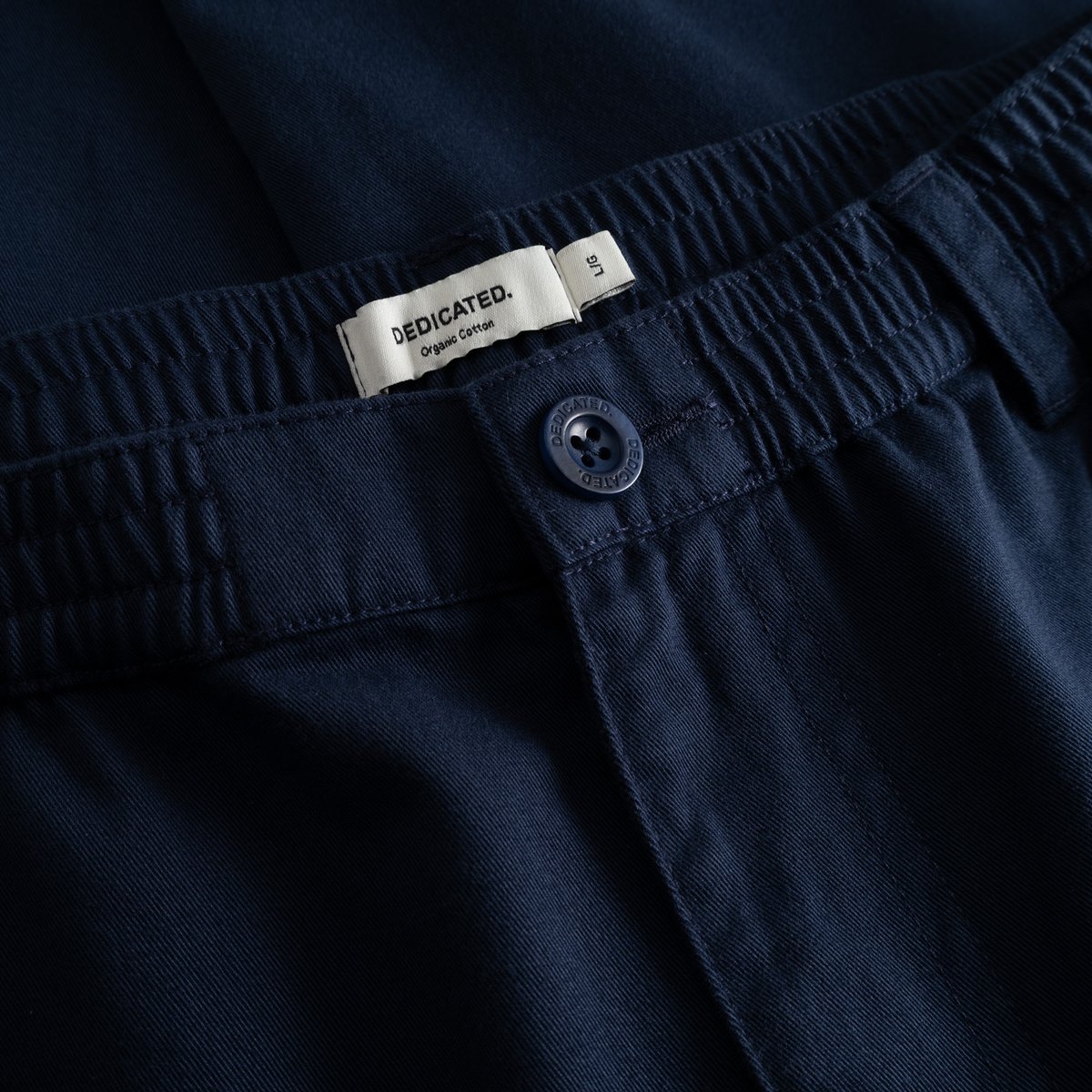 A detailed shot of the elasticated waistband on the navy Hudiksvall Chino Pants, showing the branded button and label.