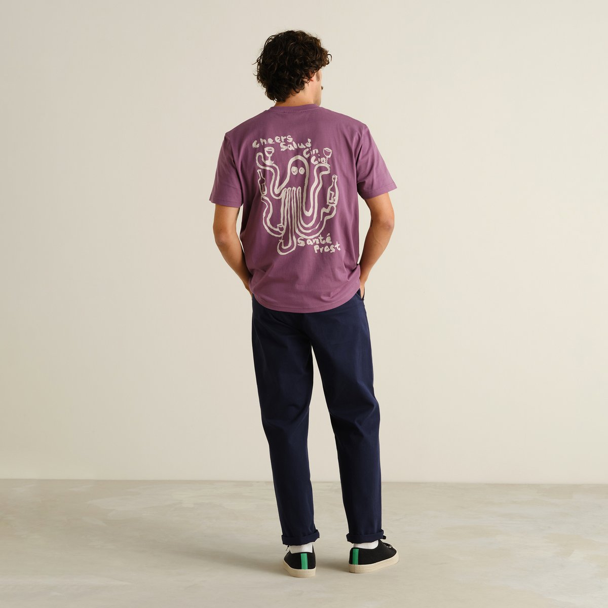 Back view of a man wearing the navy Chino Pants Hudiksvall, styled casually with a purple graphic t-shirt and black sneakers.