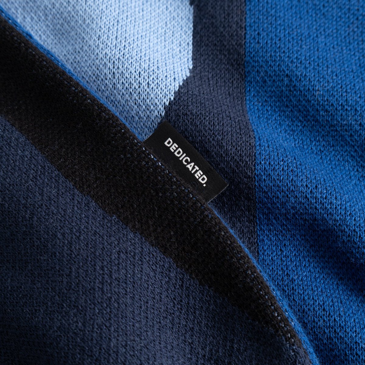 Close-up shot showing the fine knit texture and the black 'DEDICATED.' label on the Sweater Arendal Wavy Stripe Blue.