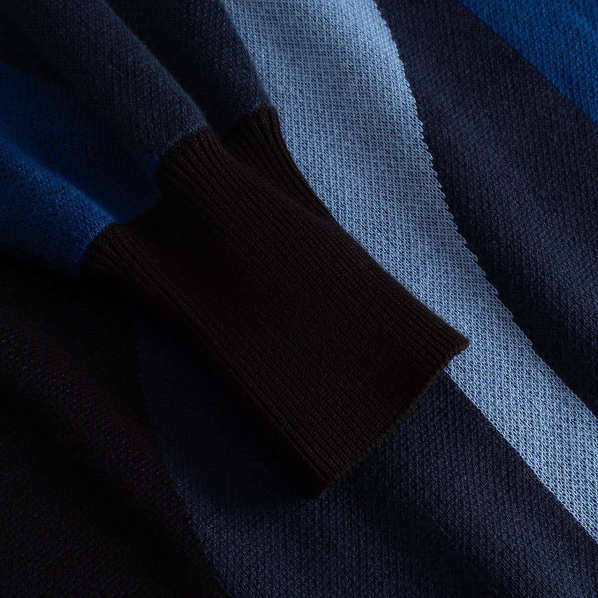 A close-up view of the jacquard knit sleeve of the Dress Nikkala, highlighting the dark ribbed cuff and wavy blue stripes.