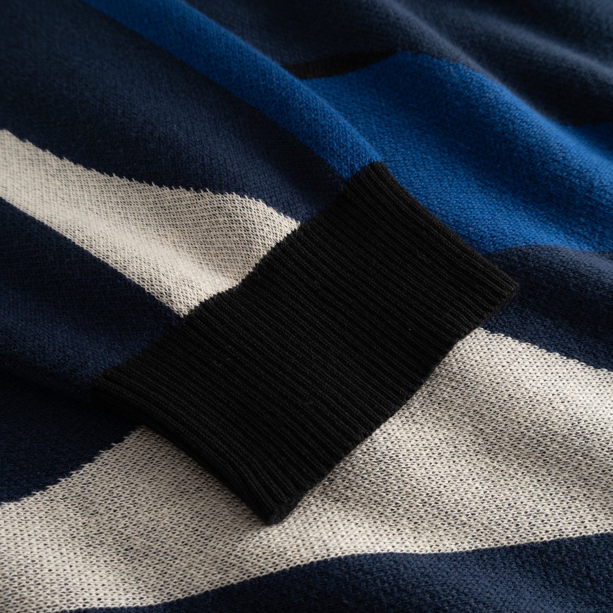 A detailed close-up of the Sweater Mora Wavy Stripe, highlighting the soft jacquard knit and contrasting black ribbed cuff.