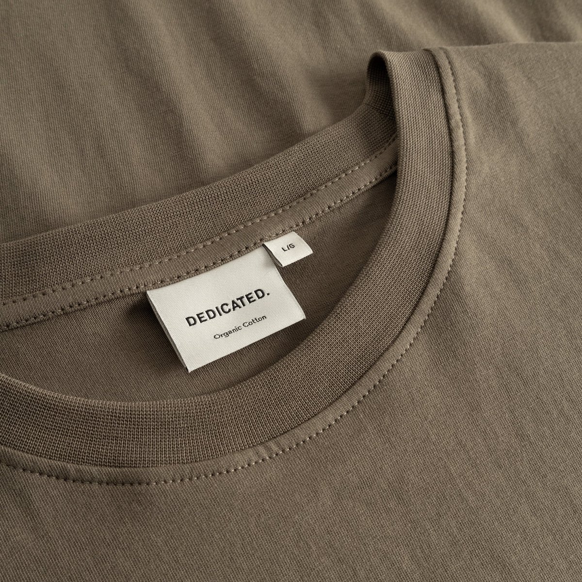 A close-up of the T-shirt Stockholm in Bungee Green, showing the ribbed neckline and the Dedicated brand label.