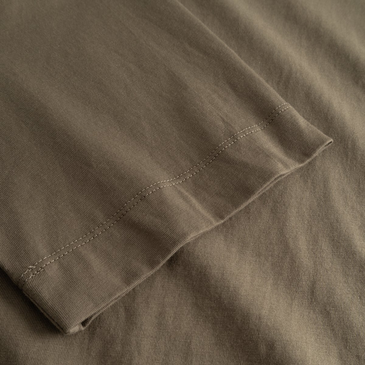A detailed close-up of the sleeve on the T-shirt Vadstena Base in Bungee Green, showing the fine stitching and fabric.