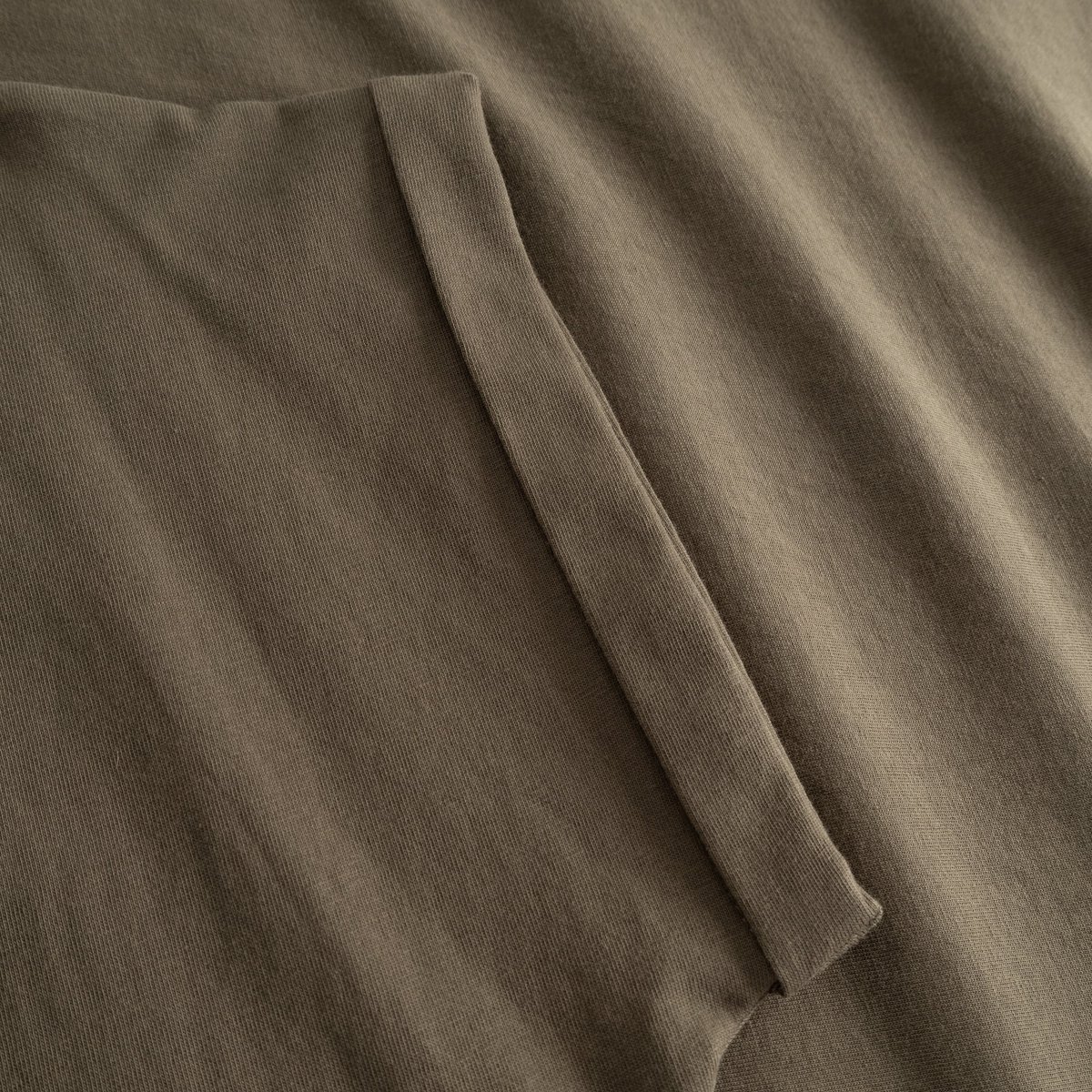 Close-up of the folded sleeve detail on the Visby t-shirt in Bungee Green, crafted from soft organic cotton.