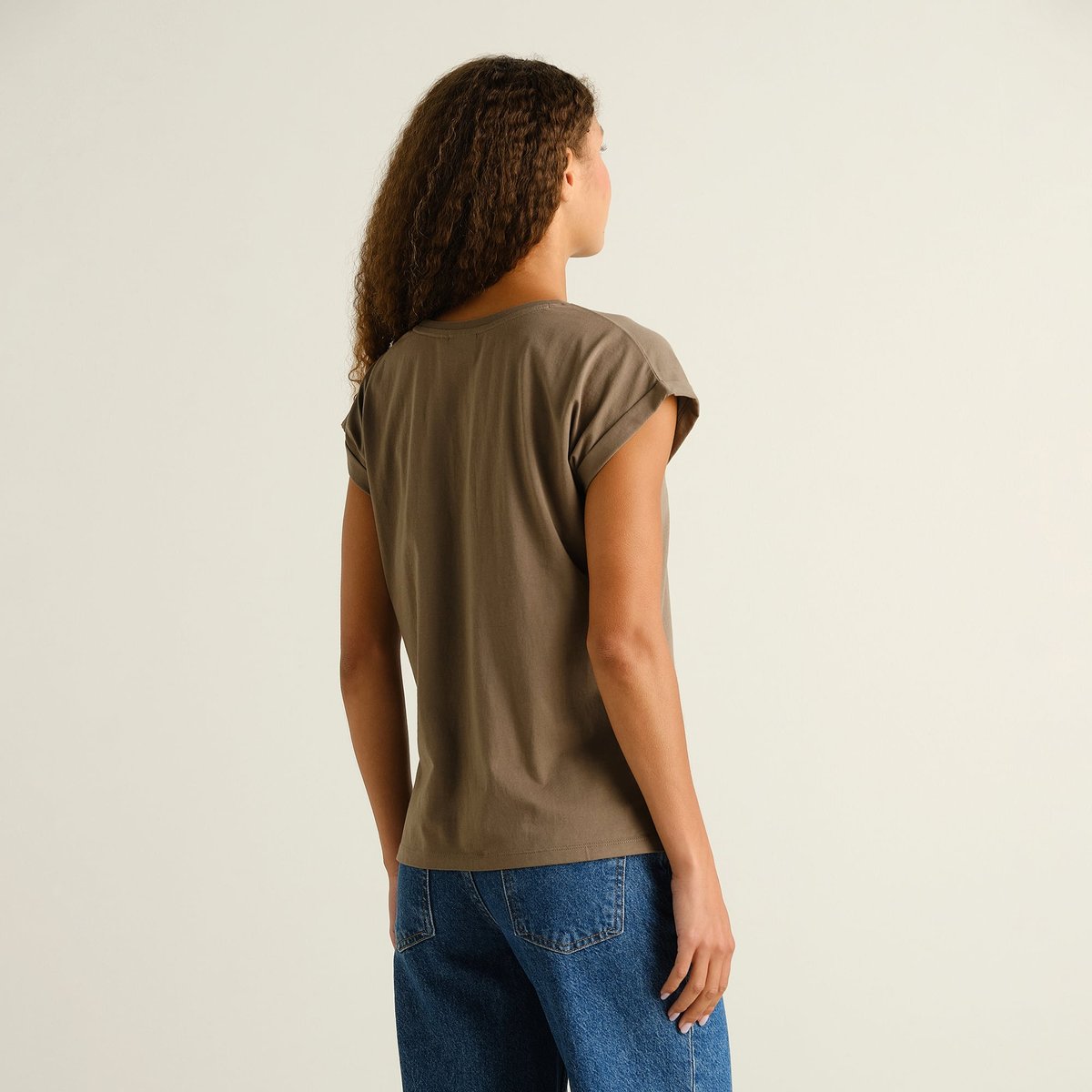 Back view of a woman wearing the slim-fit T-shirt Visby Base in Bungee Green, featuring folded sleeves.