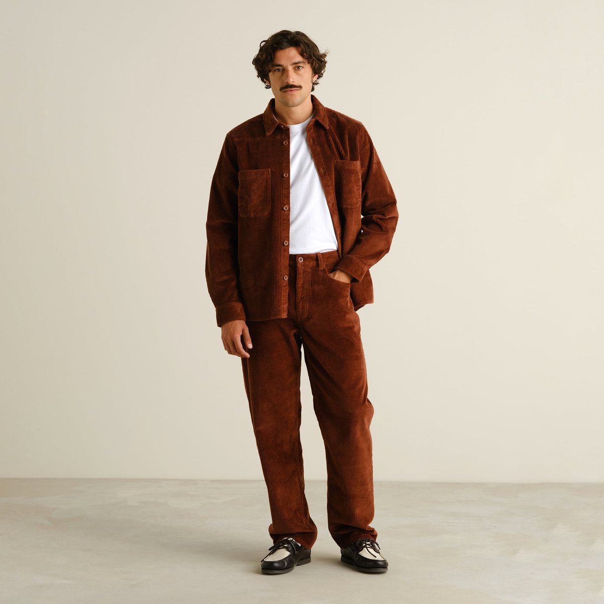 Model styles the Kil Corduroy Shirt in Cappuccino Brown open over a tee with matching trousers for a relaxed, confident look.