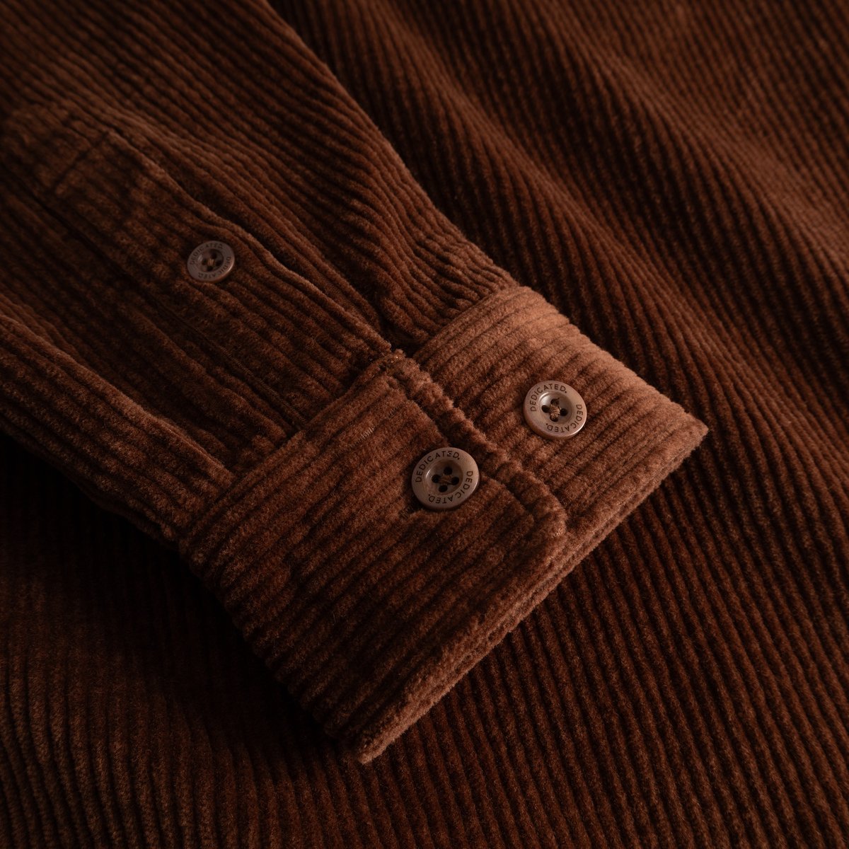 Close-up detail shot of the Shirt Kil Corduroy in Cappuccino Brown, highlighting the rich texture and branded cuff buttons.
