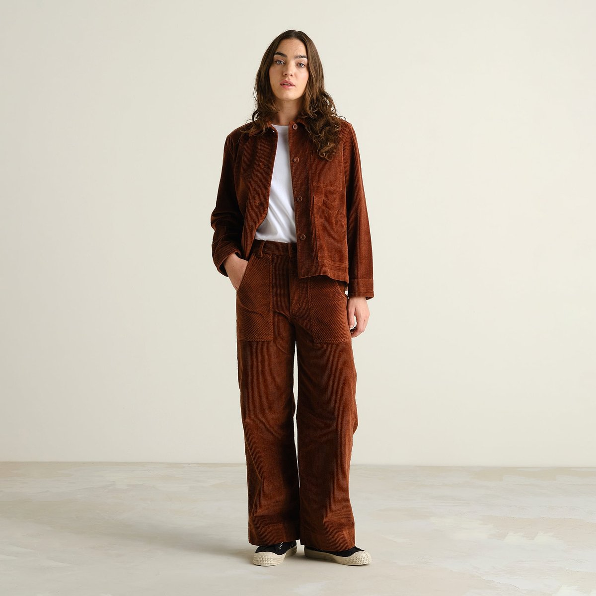 A model rocks a full cappuccino brown corduroy look, featuring the wide-leg Vara Workwear Pants and a matching jacket.