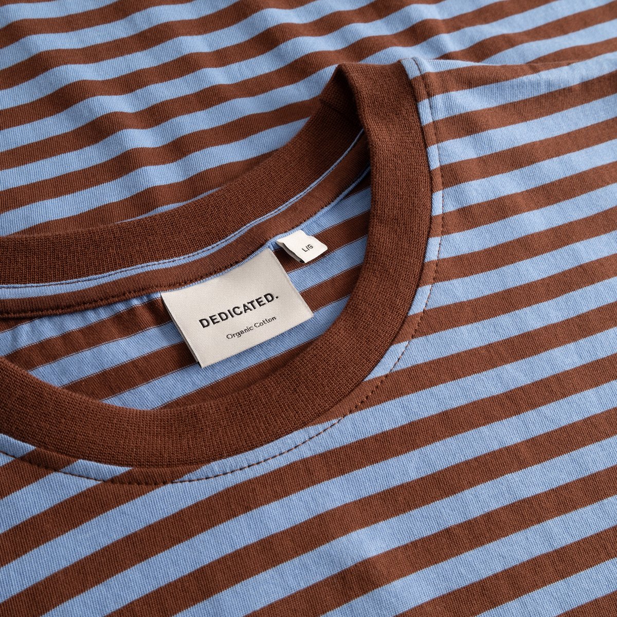 Close-up of the Stockholm T-shirt collar, with cappuccino brown and cornflower blue stripes and the Dedicated label.