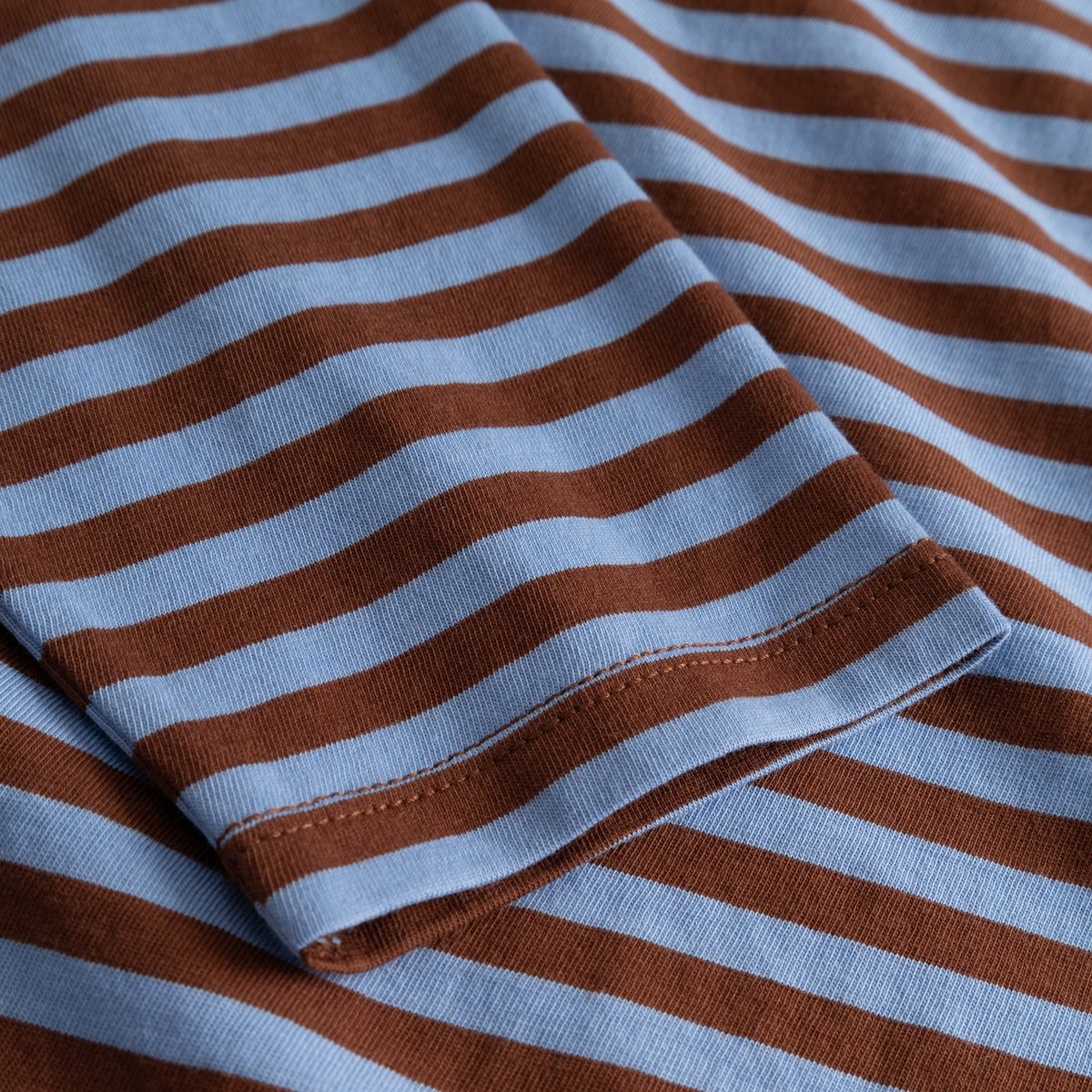 Close-up of the sleeve on the Top Humledal, showing the cappuccino brown and cornflower blue striped organic cotton fabric.
