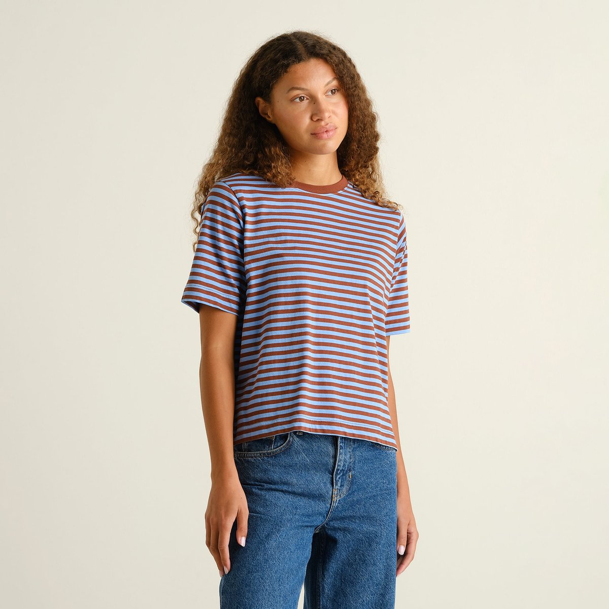 A woman models the relaxed-fit Vadstena t-shirt with cappuccino brown and cornflower blue stripes, paired with jeans.
