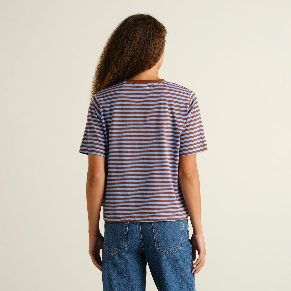 Back view of the striped T-shirt Vadstena in Cappuccino Brown and Cornflower Blue, styled with classic blue jeans.