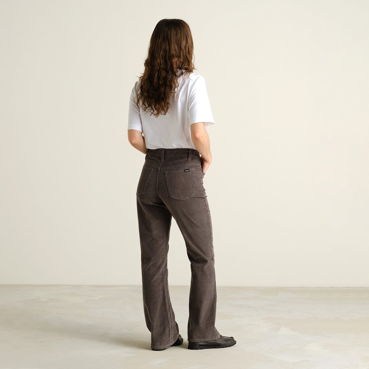 Rückansicht einer Frau, die die Bootcut-Cordhose Ryda in Rock Grey trägt.