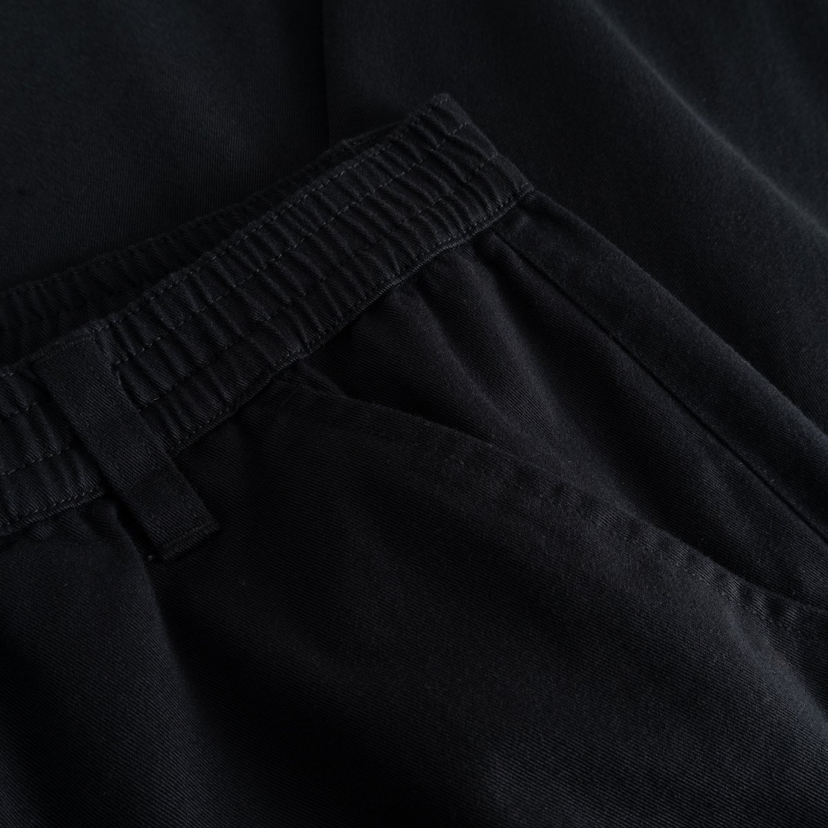 A detailed look at the elasticated waistband of the black Hudiksvall Chino Pants, crafted from organic cotton twill.