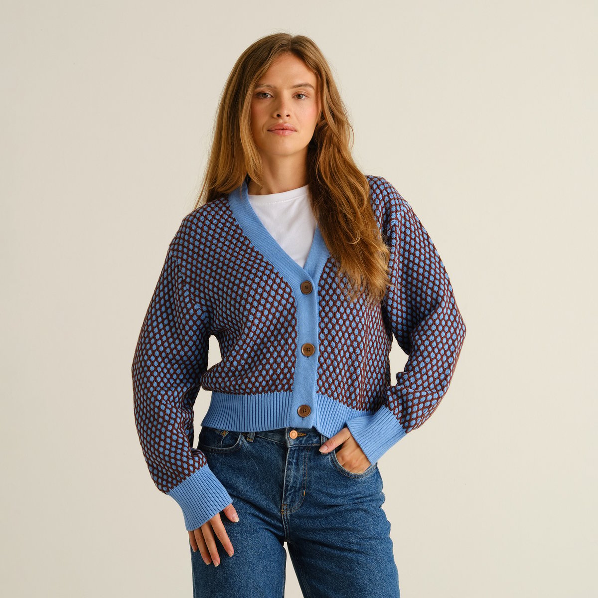 En kvinna bär Cardigan Kanan Bubble Knit i blåklintsblått och cappuccinobrunt, stylad med jeans och en vit t-shirt.