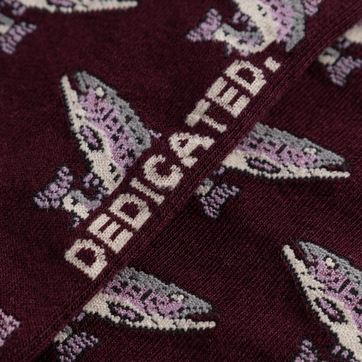 A close-up shot of the Dedicated Sigtuna socks in fig, showing the detailed jacquard knit of the fun trout pattern.