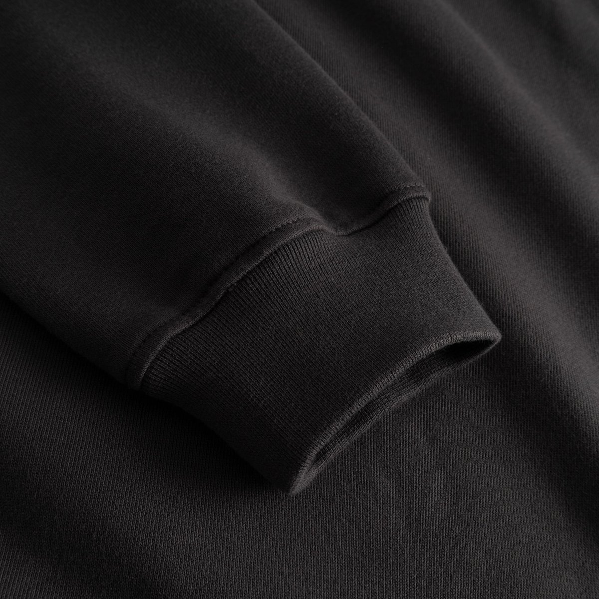The comfortable ribbed cuff of the charcoal Ystad Painted Bird sweatshirt, shown in a detailed close-up.