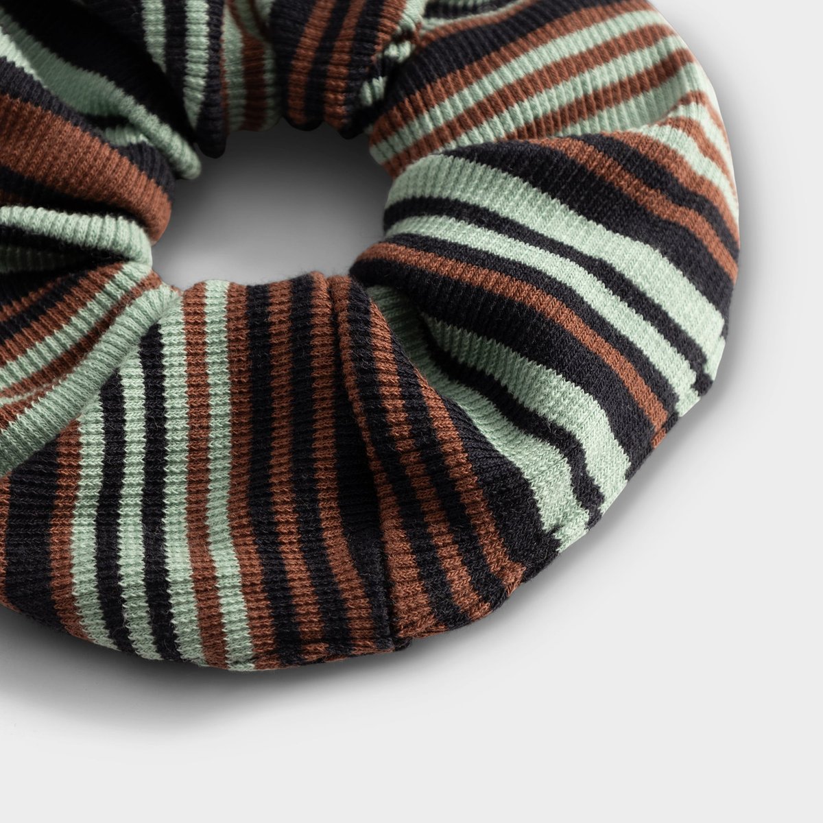 A detailed close-up of the Irregular Stripe Green scrunchie, showing its soft ribbed texture and colourful pattern.