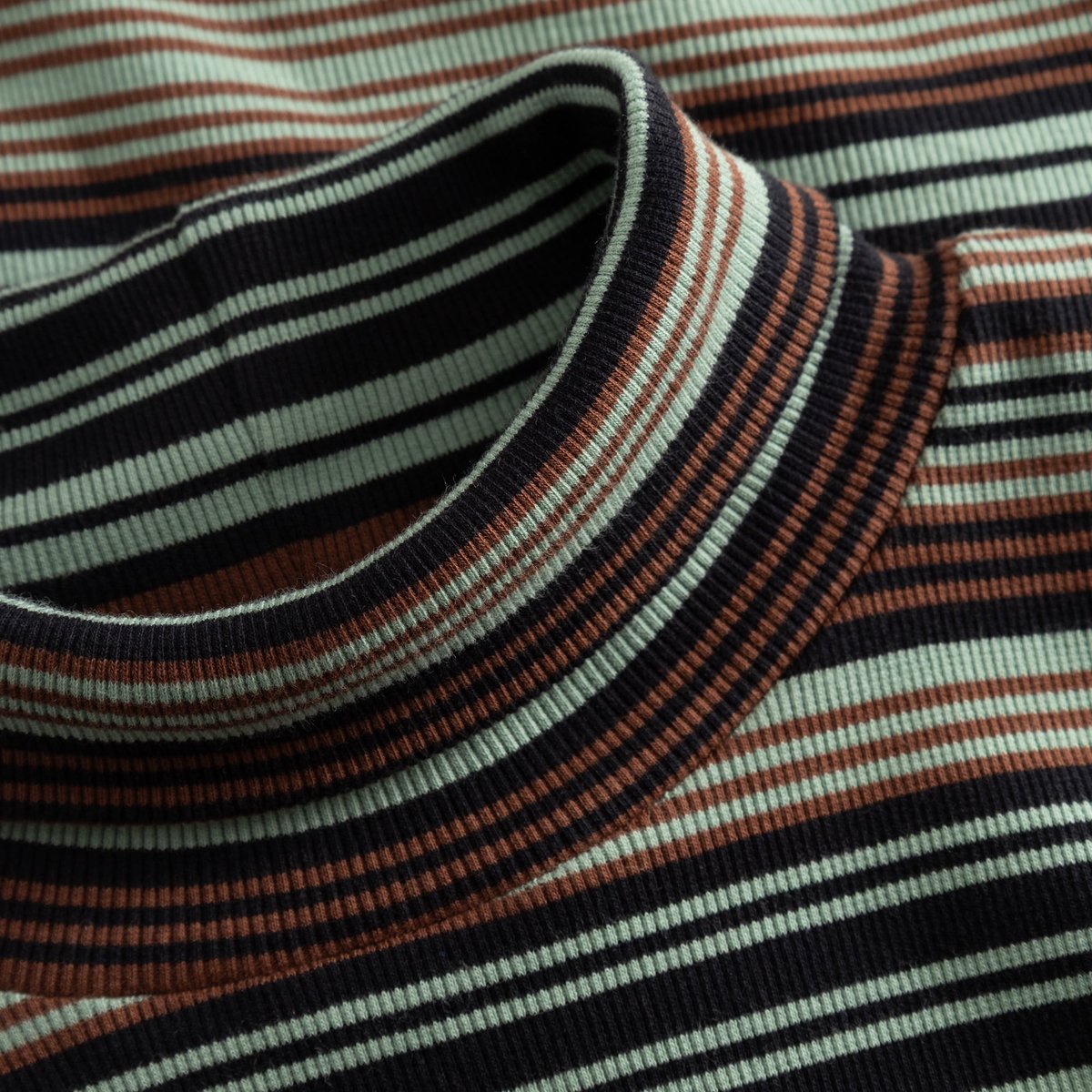 Close-up of the ribbed turtleneck collar of the Lunsen dress, featuring irregular stripes in green, brown and black.