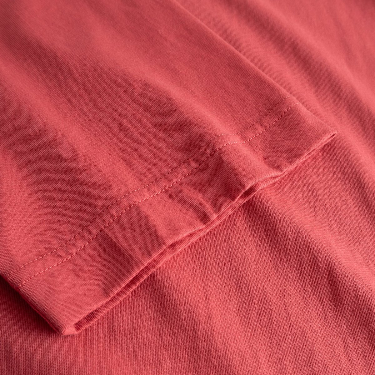A close-up view of the sleeve hem on the T-shirt Vadstena Paws For a Moment in Holly Red, showcasing the soft fabric.