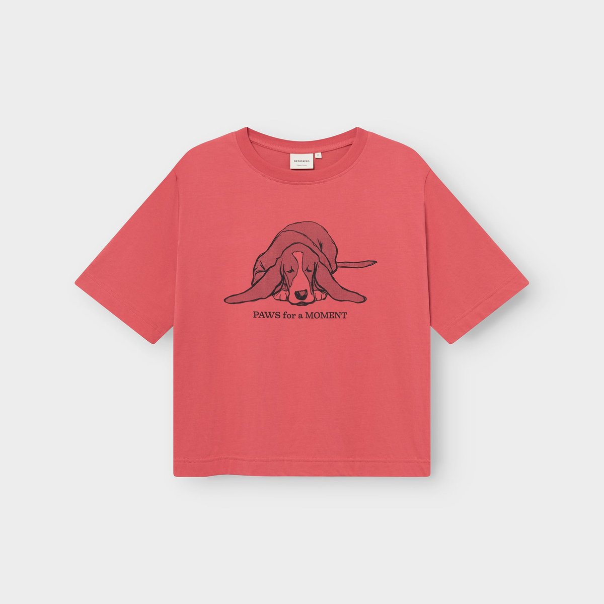 A flat lay view of the T-shirt Vadstena in Holly Red, featuring a print of a sleeping basset hound and 'Paws for a moment'.