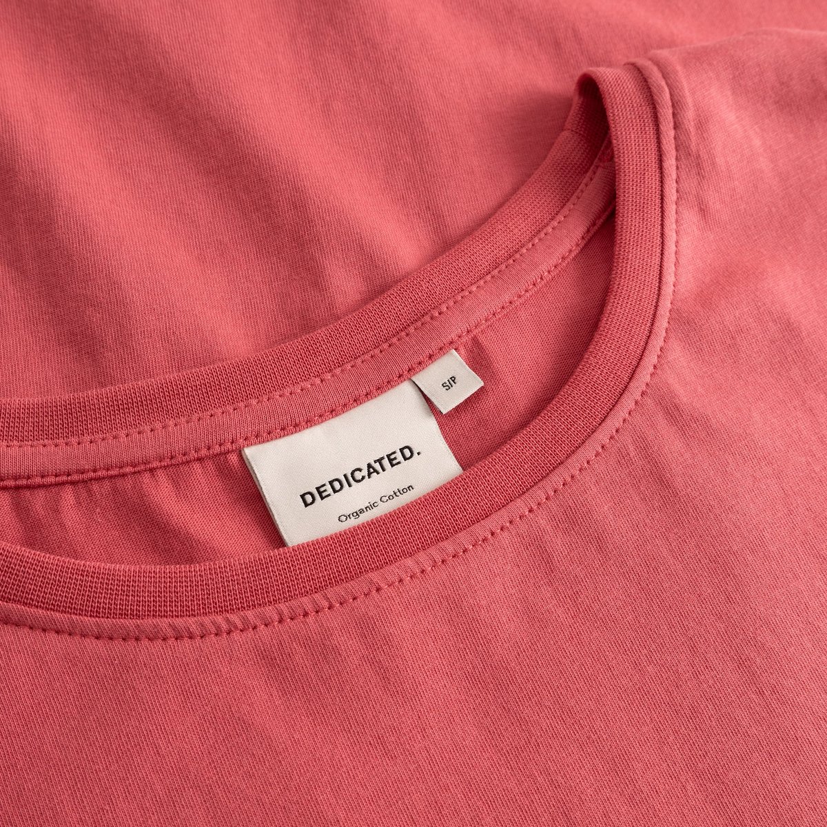 Detailed close-up shot of the T-shirt Visby Base in Holly Red, showing the ribbed neckline and Dedicated brand label.