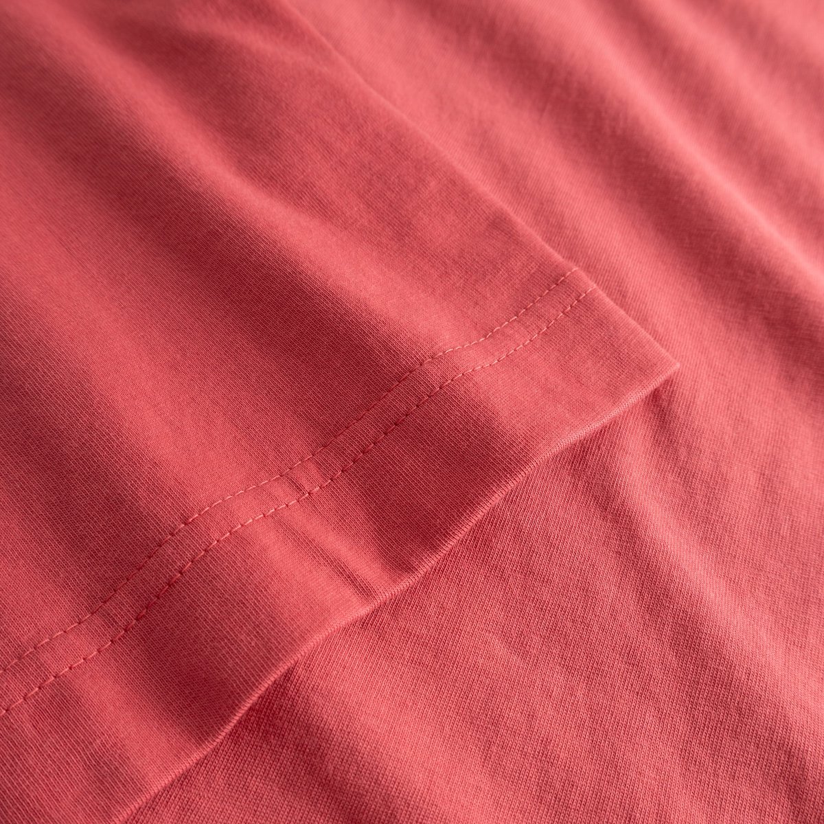 A detailed view of the sleeve on the Vadstena Base T-shirt, showing off the beautiful Holly Red organic cotton fabric.