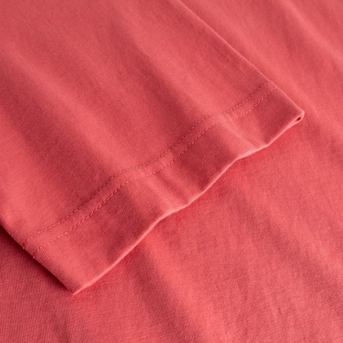 A detailed close-up of the sleeve on the T-shirt Vadstena in Holly Red, crafted from soft organic cotton.