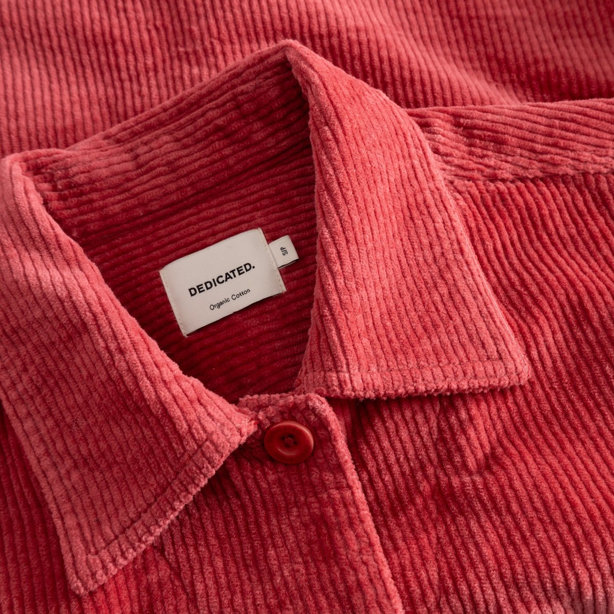 Close-up shot of the Dedicated brand label on the collar of the Stiby Corduroy Jacket in Holly Red.