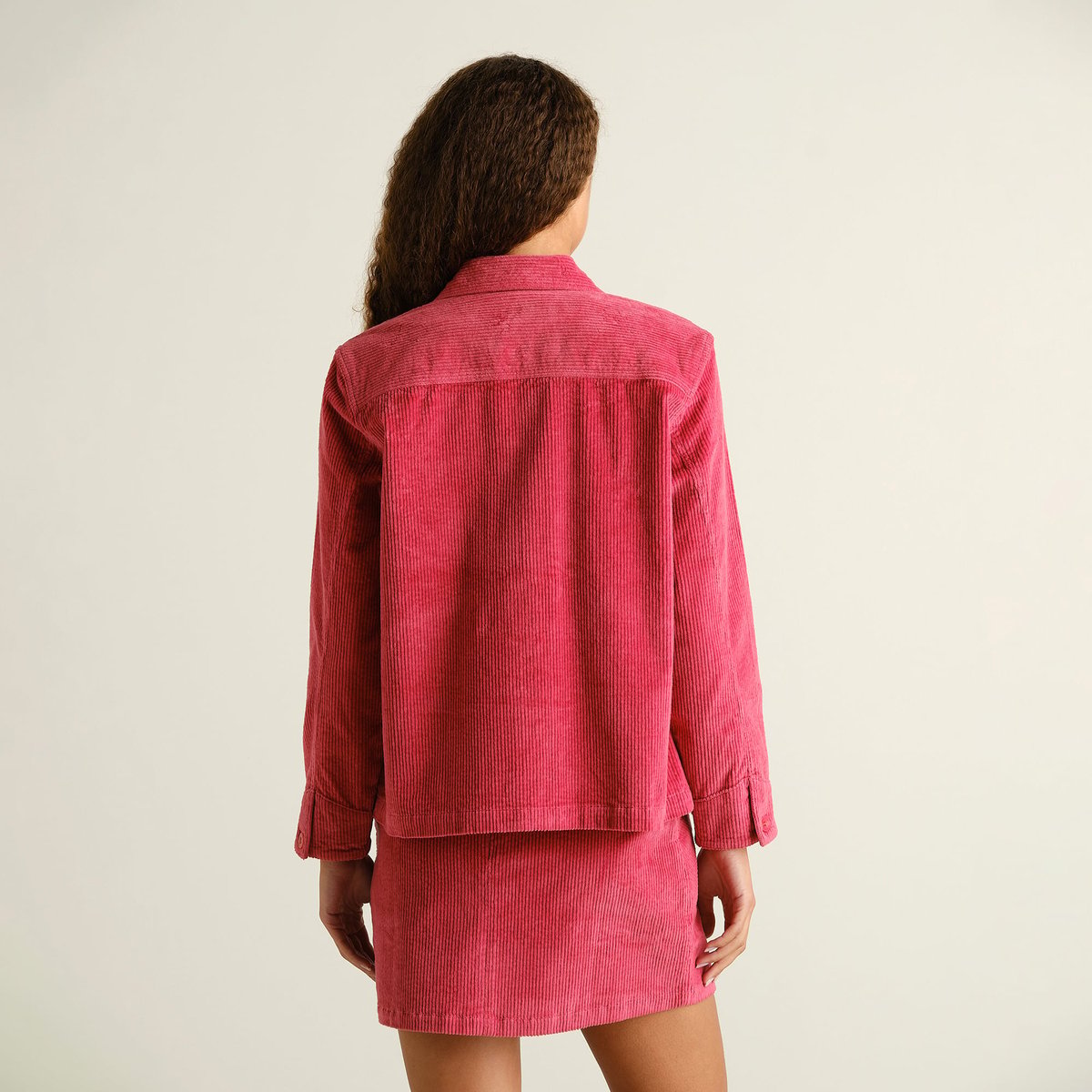 The Stiby Corduroy Jacket in Holly Red, seen from the back on a model wearing the matching skirt for a fun, coordinated look.