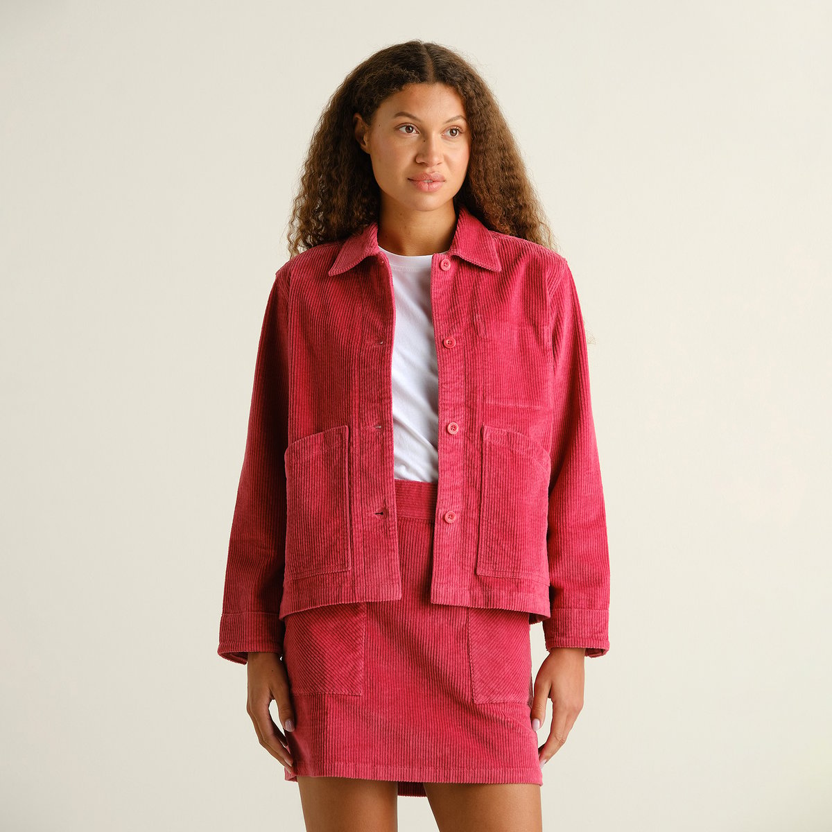 A model styles the Holly Red Stiby Corduroy Jacket with its matching skirt for a vibrant, coordinated look in our studio.