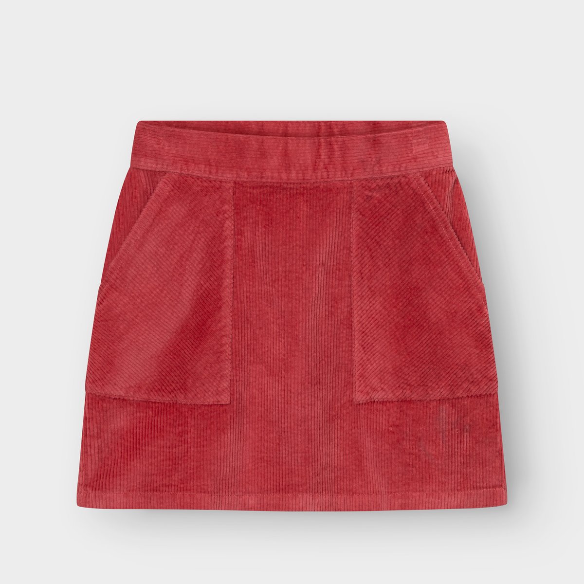 Studio shot of the Skirt Majorna Corduroy in Holly Red, a short A-line skirt with two large front patch pockets.