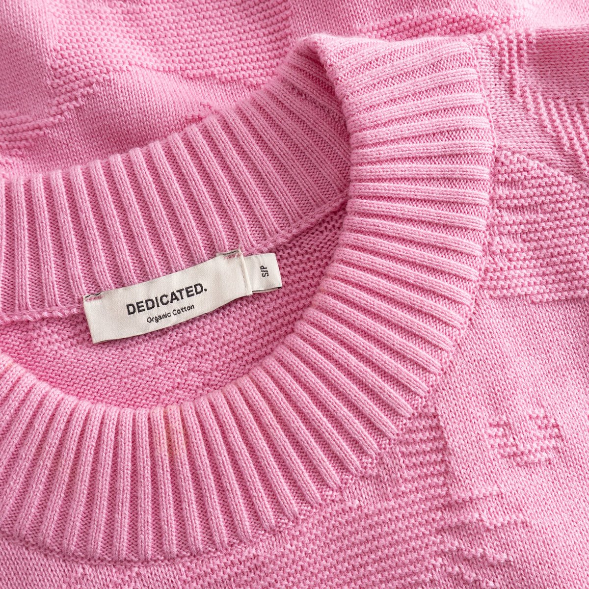 Detailed shot of the Husie sweater in Moonlite Pink, highlighting the ribbed neckline and the playful cat pattern knit.