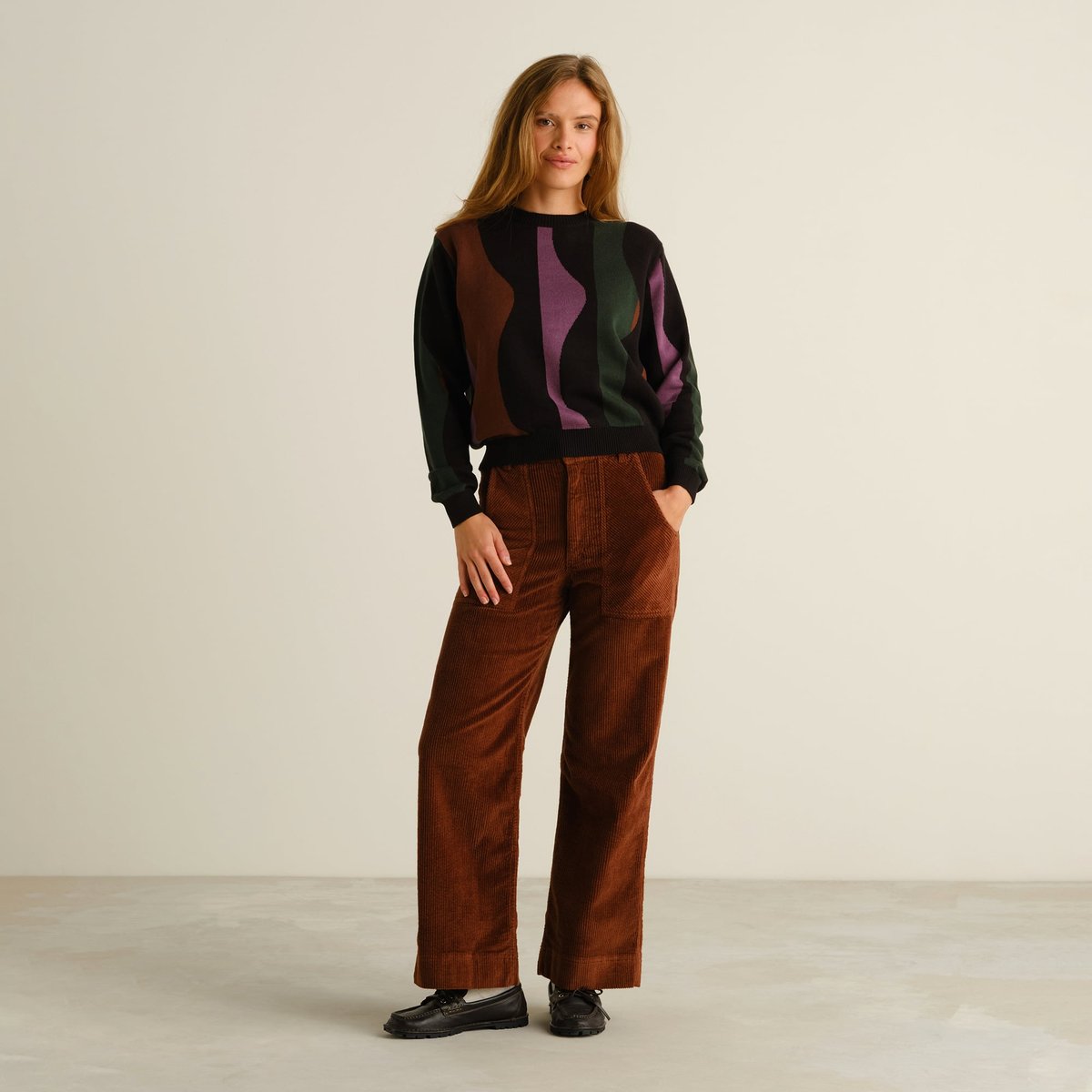 Model wears the Sweater Arendal Wavy Stripe Multi Color, styled with brown corduroy trousers and black loafers.