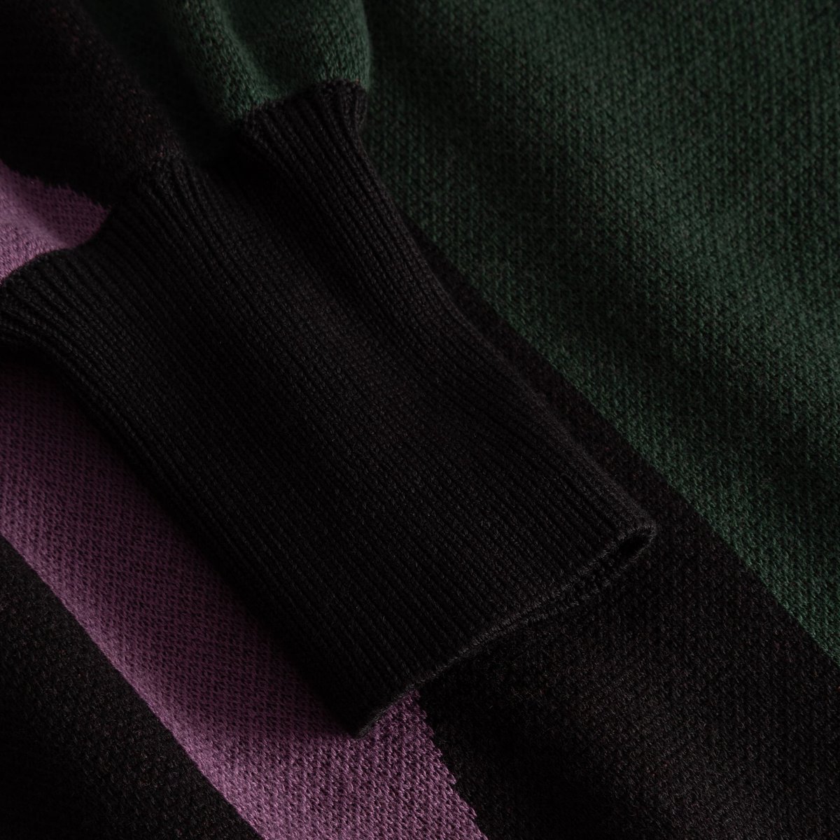 A detailed close-up of the multi-colored Dress Nikkala, focusing on the fine knit texture and the soft, black ribbed cuff.