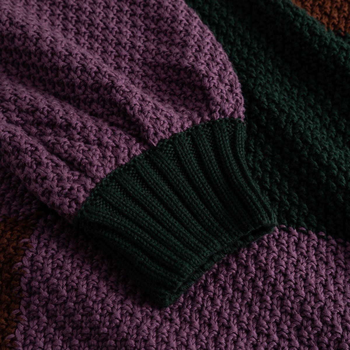 Detailed shot of the Sweater Gotland Blocked Check, focusing on the chunky purple knit sleeve and dark green ribbed cuff.