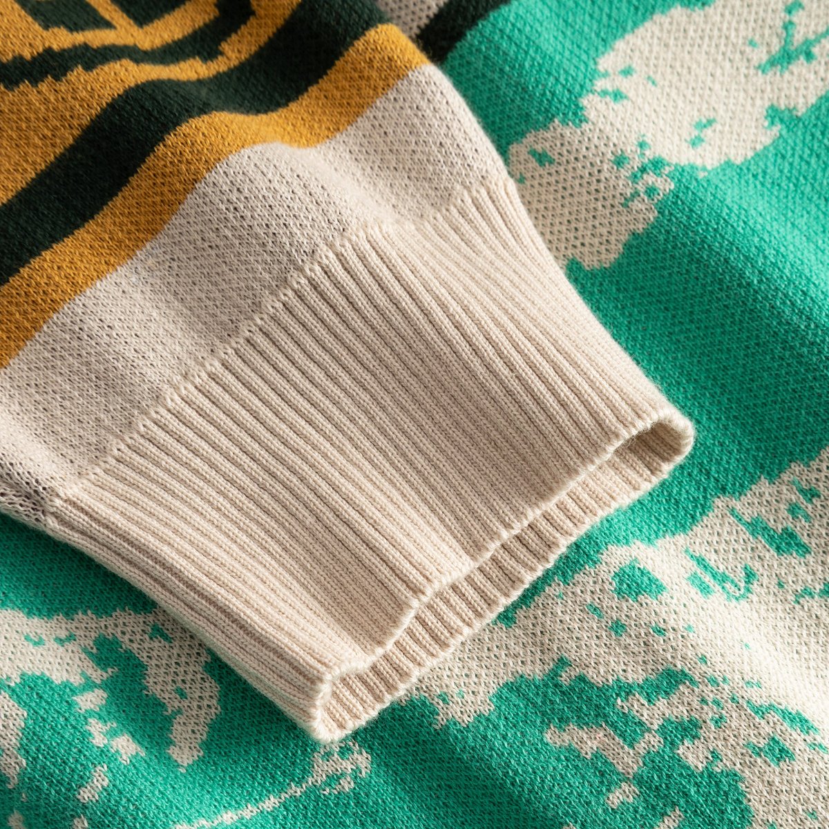 Närbild på den ribbstickade mudden och den färgglada, jacquardstickade ärmen på Cardigan Delsbo Retro Ski Blocks.