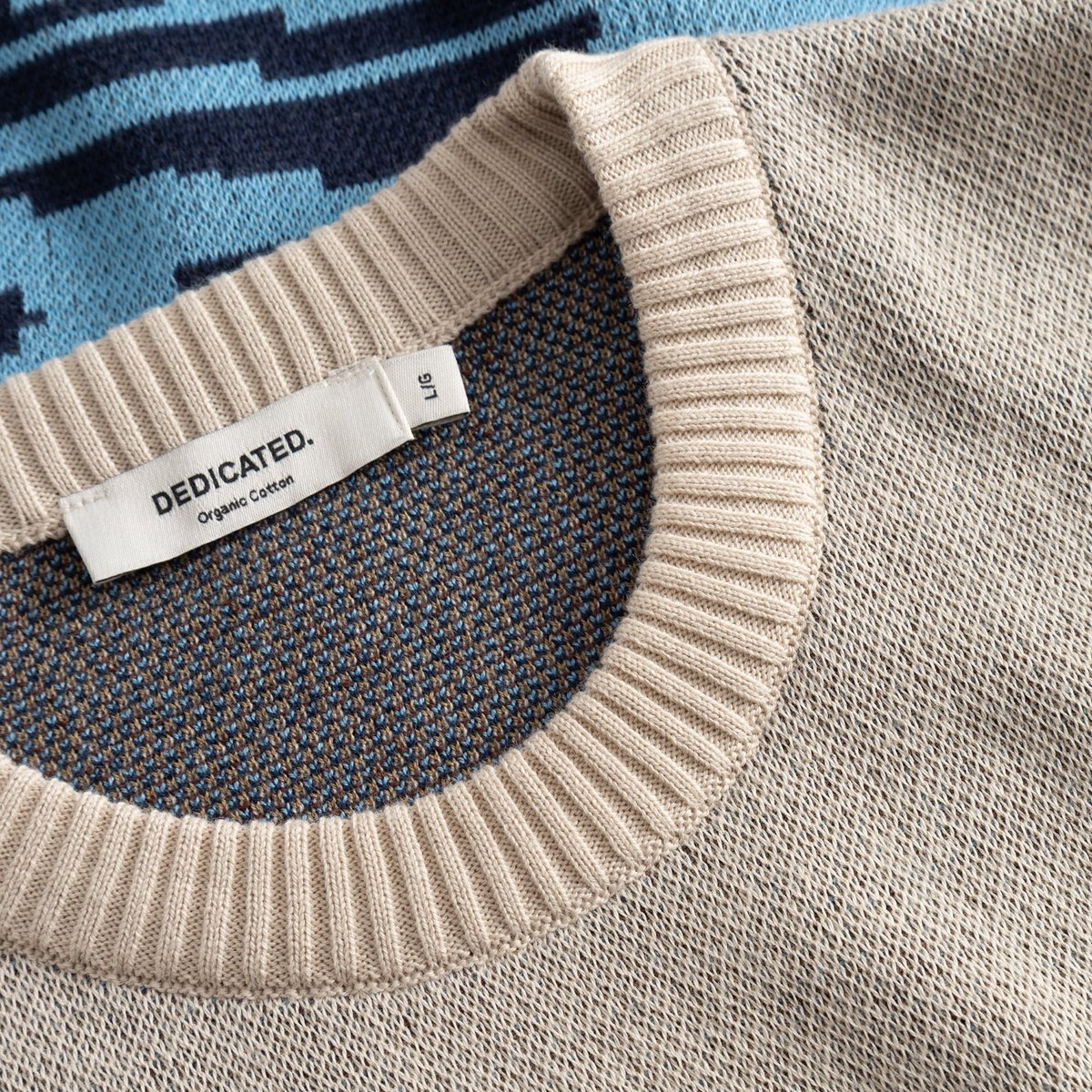 Detail shot of the Sweater Mora Man and Sea, showing the texture of the jacquard knit and the ribbed neckline with brand tag.