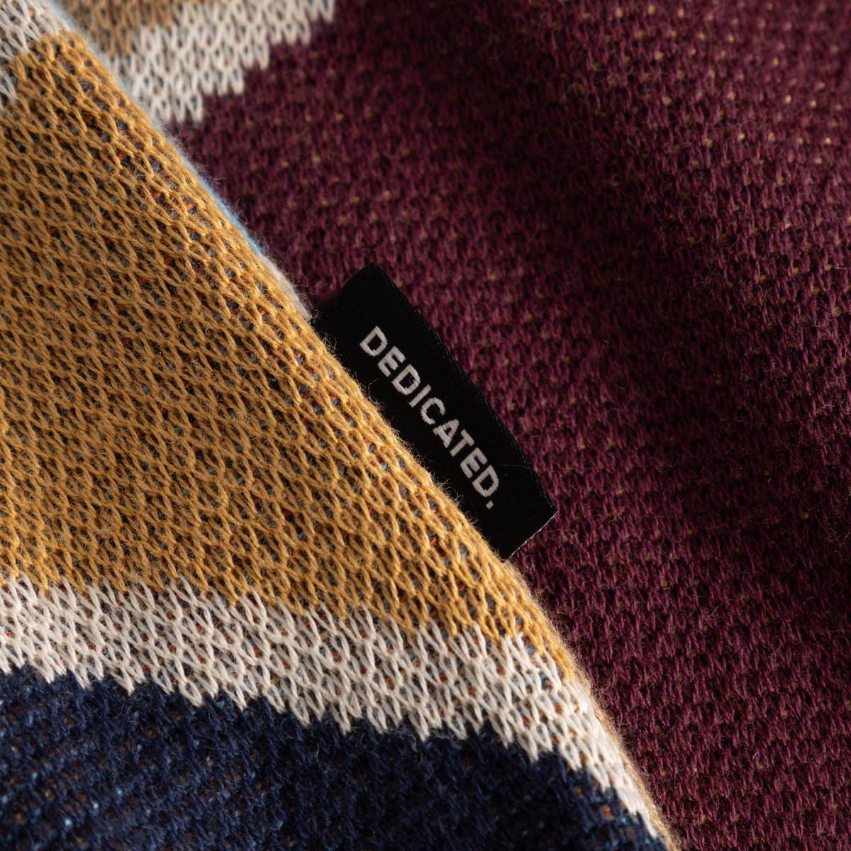 A detailed look at the rich texture and multi-color jacquard knit of our Sweater Mora, finished with the Dedicated logo tag.