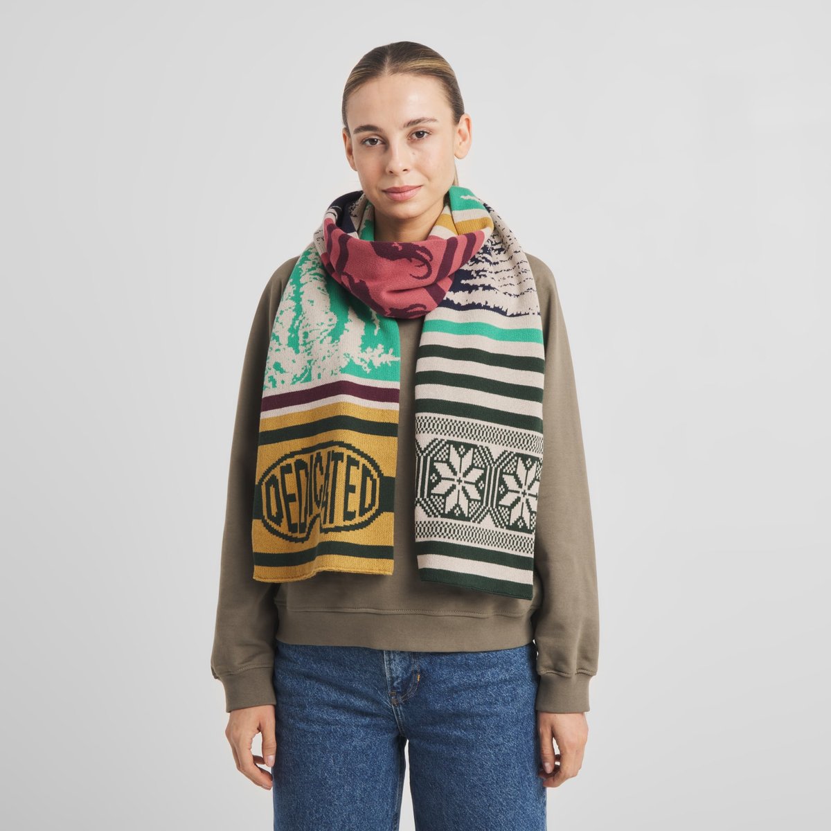 Model wearing the colorful Scarf Rossberga Retro Ski Blocks over a casual sweatshirt, showcasing its unique mix of patterns.