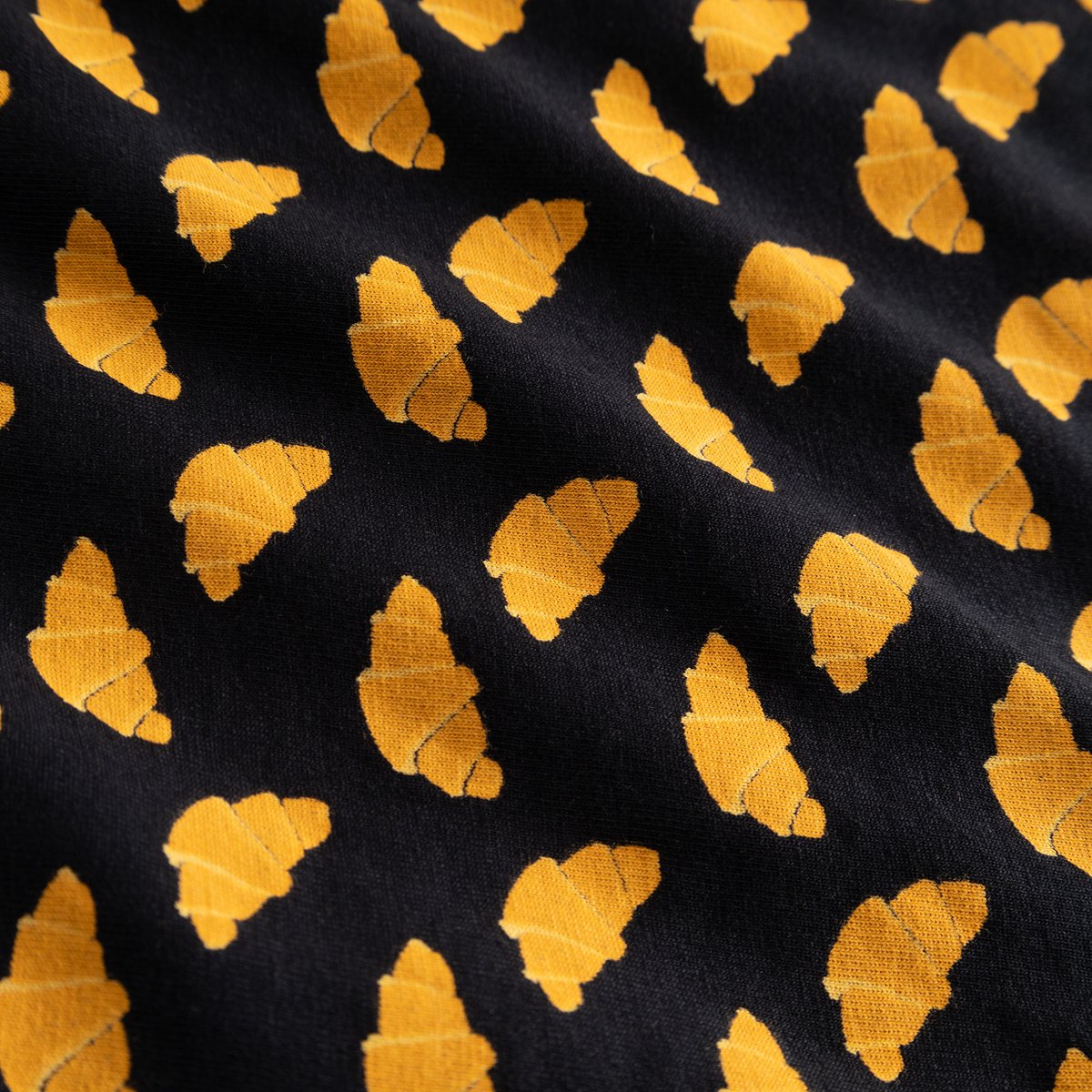 A close-up shot of the black fabric for the Boxer Briefs Kalix, showing the fun all-over print of yellow croissants.