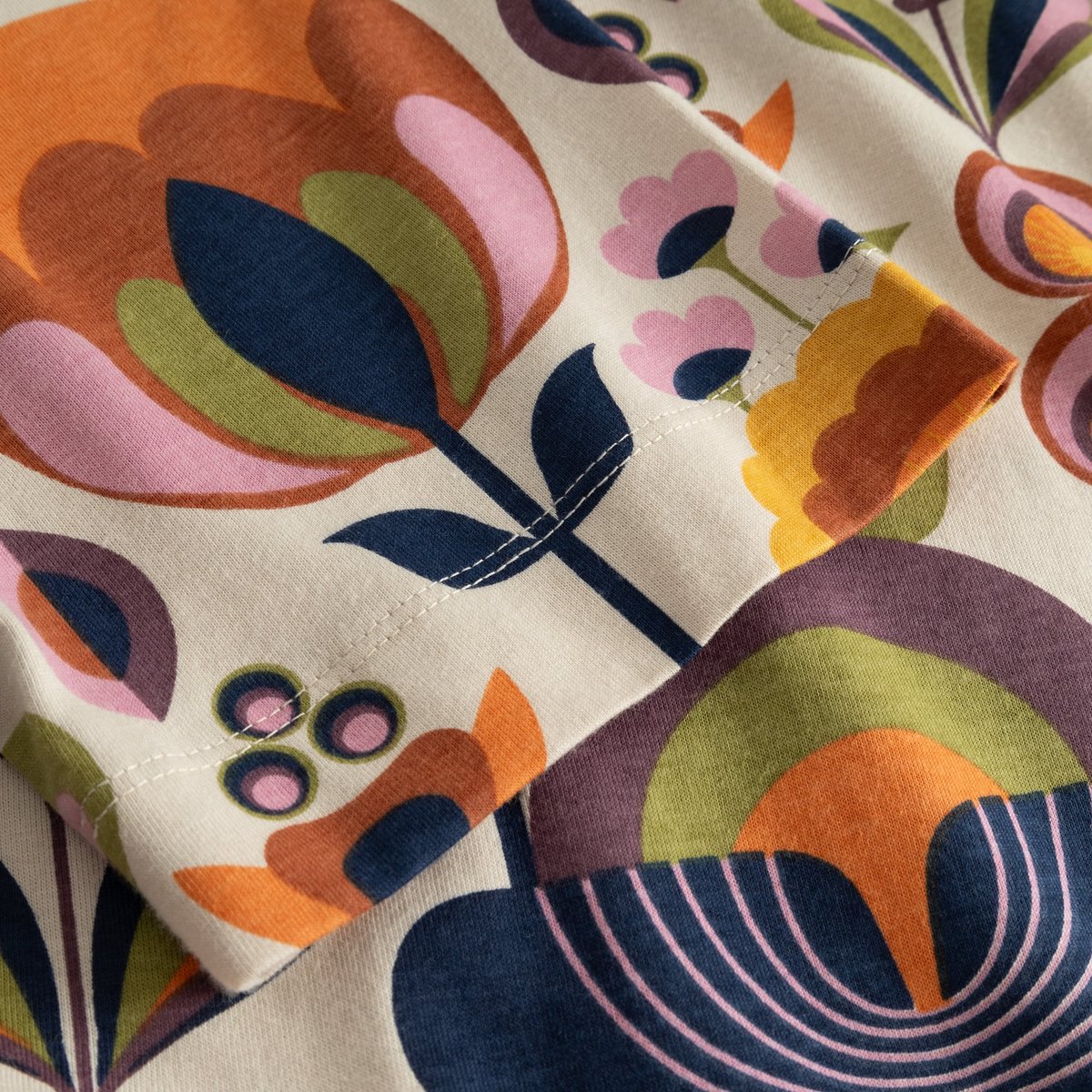 Close-up of the T-shirt Vadstena's sleeve, showing the vibrant retro-inspired Autumn Harvest print and fine stitching detail.