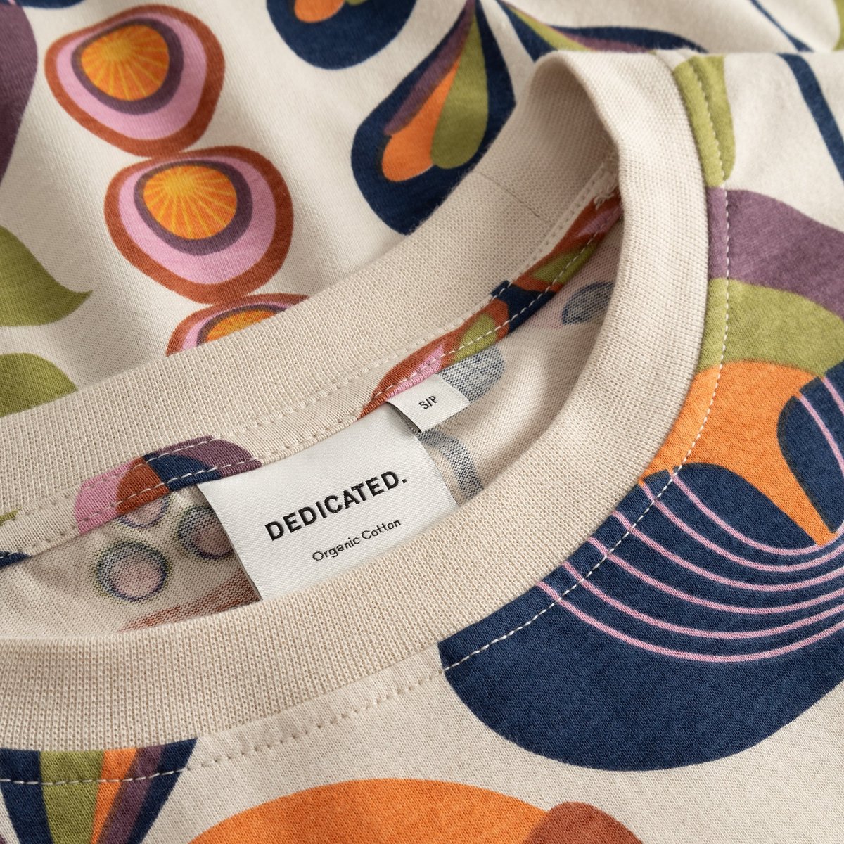 Close-up of the neck label and vibrant Autumn Harvest pattern on the organic cotton T-shirt Vadstena.