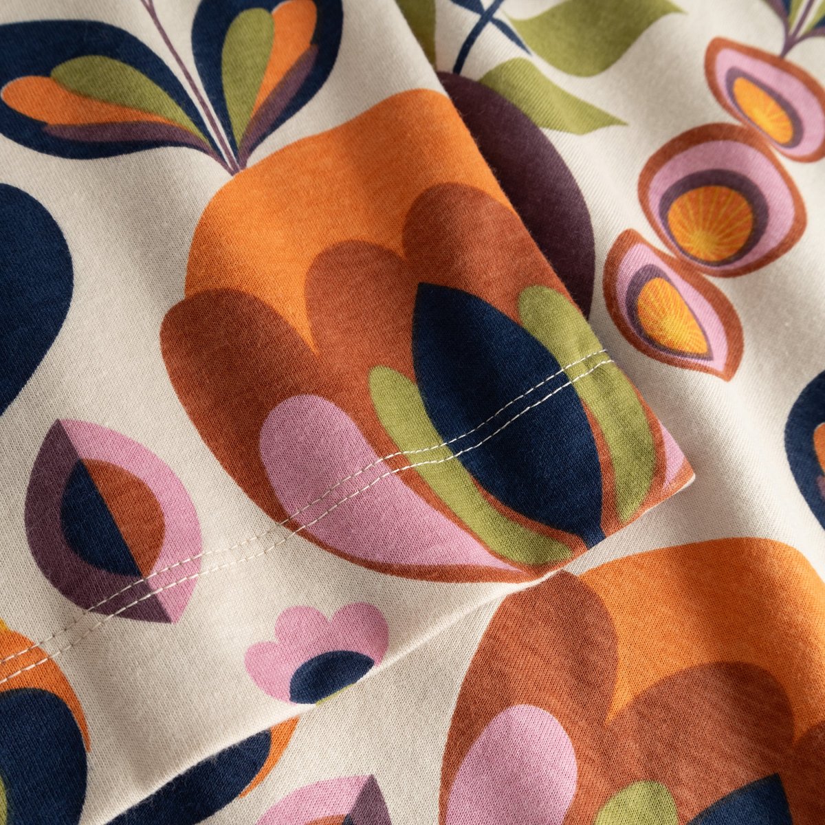 A detailed close-up of the T-shirt Vadstena, highlighting the colorful retro-style Autumn Harvest print on the sleeve.
